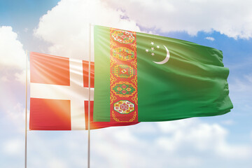 Sunny blue sky and flags of turkmenistan and denmark