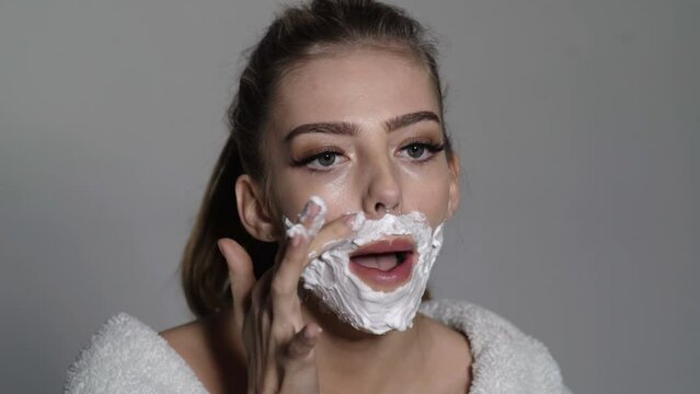 Woman shaving face. Funny young girl shaves her face like a man. Mustache, beard disposable razor.