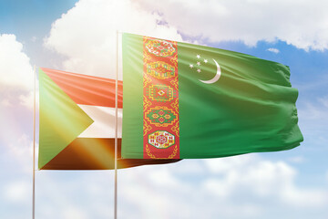 Sunny blue sky and flags of turkmenistan and sudan