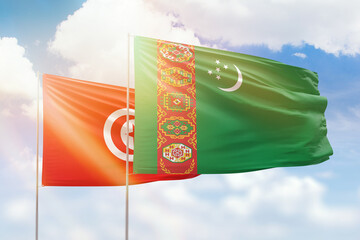 Sunny blue sky and flags of turkmenistan and tunisia