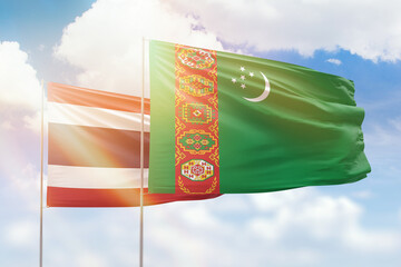 Sunny blue sky and flags of turkmenistan and thailand