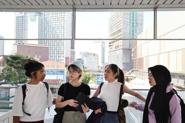 Four young attractive Asian group woman friends colleagues students talk walk discuss mingle...