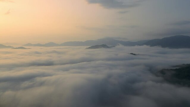 Aerial timelapse: Sunrise over turbulent fog swirling around mountain peaks