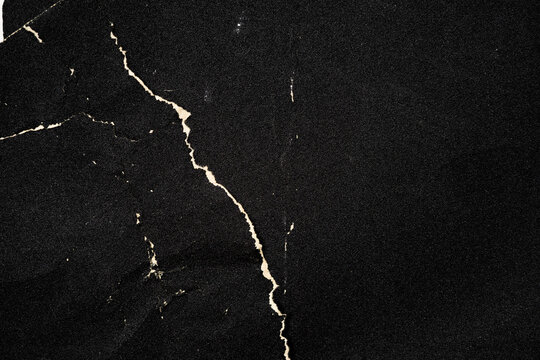 Crumpled black paper with a detailed texture. Close up the paper with white cracks. Rough paper texture for background.