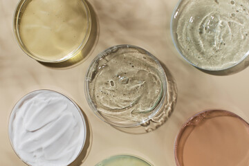 Different skincare products in Petri dishes and shadow on yellow background
