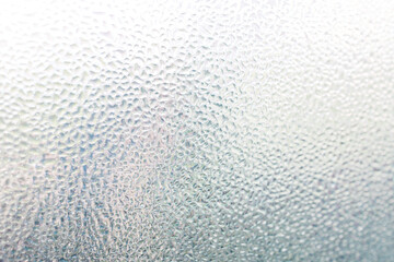 water droplets of humidity condensation on window glass seen from indoor with backyard bokeh in the background