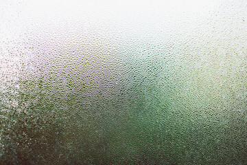 water droplets of humidity condensation on window glass seen from indoor with backyard bokeh in the background - obrazy, fototapety, plakaty