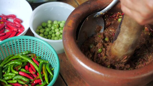 Chilies and spices are being finely pounded into a curry paste using a mortar.preparing an ingredient for cooking Thai food,Shrimp Paste Chili Paste,Thai Nam Prik Kapi Recipe