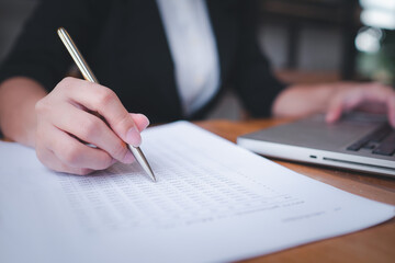 Asian business woman Use the pen to find the numbers. Analysis and Finance and Banking Technology...