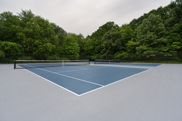 Blue tennis court with white lines and gray out of bounds	