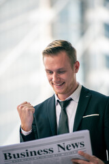 Young businessman reading a good news on Newspaper news with excited in the morning.