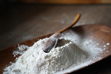 Wooden spoon with flour on the countertop in the kitchen.