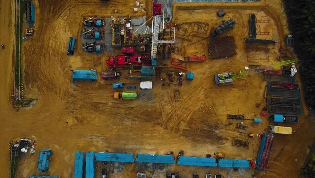 Cinematic Drone Shot of Onshore Drilling and Workover Rig structure and Rig equipment for oil exploration and exploitation in the middle of jungle surrounded by palm oil trees during sunset time.