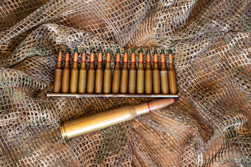 Bullets lie on a green camouflage background, military weapons