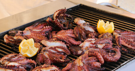 grilled octopus with tentacles and sliced lemon to garnish the fish dish in the restaurant specializing in fish specialties - obrazy, fototapety, plakaty