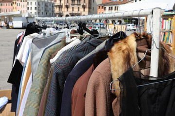 Fototapeta na wymiar old jacket with fur collar and other vintage clothes for sale in the outdoor used clothes stalls