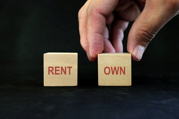 Rent versus own and ownership concept. Hand choosing word own over rent.