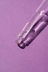 Naklejka premium Pipette with serum or cosmetic liquid close-up on a purple background in soft focus. Beautiful shadow in the sunlight. Skincare products , natural cosmetic. Beauty concept for face and body care