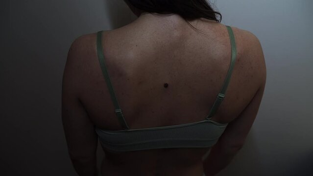 Half naked Woman standing in bra. Light is illuminating the young woman's back.