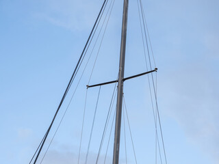 Yacht mast with ropes with blue sky in background