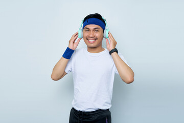 Handsome young asian man sporty fitness trainer instructor in blue headband and white t-shirt.  Makes fun Listening to music with headphones isolated over white background