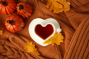 Autumn still life. Oak leaves, heart cup on knitted scarf or plaid. Ceramic pumpkin - halloween...