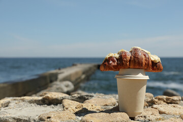 Fototapeta na wymiar Concept of amazing breakfast near sea with croissant and paper cup of drink