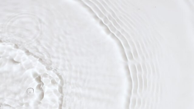 Slow motion closeup water surface texture splash and ripples on white background