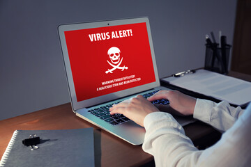 Young woman working on laptop late in evening. Antivirus concept