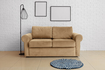 Interior of living room with sofa and lamp near white brick wall