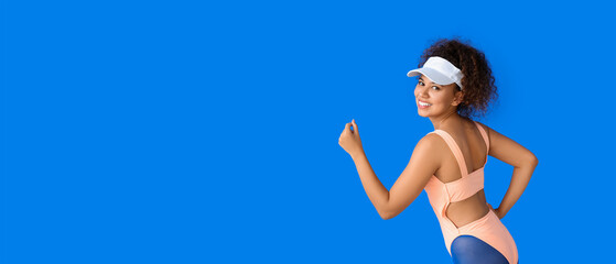 Obraz na płótnie Canvas Sporty running African-American woman on blue background with space for text