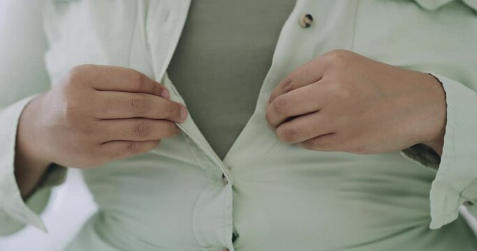 Portrait of sad plus size woman struggling to button up shirt. Closeup of overweight latino woman feeling unhappy with weight, wishing to be thin. Distressed and anxious with body dysmorphia