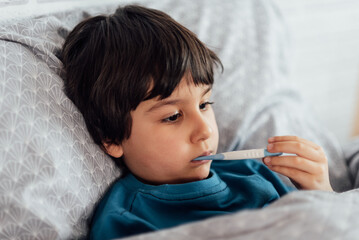Child flu sick, boy with medical thermometer in mouth, health illness. Kid with cold rhinitis, get cold © Serenkonata