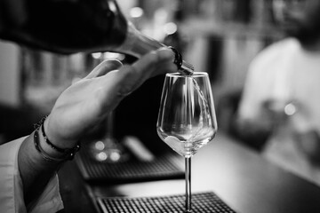 Shallow depth of field (selective focus) details with sparkling wine being poured into a glass at a bar.