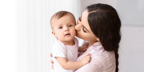 Happy mother kissing her cute little baby at home