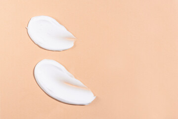 Smears of a white cosmetic product on a beige background. Skin and body care, cream texture top view.