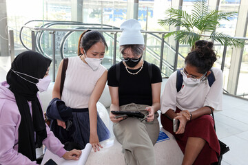 Four young attractive Asian group woman friends colleagues students indoor building sit on modern...