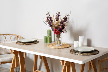 Dining table with beautiful setting near light wall