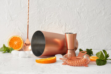 Set of copper cocktail utensils and ingredients on light table