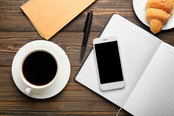 Composition with cup of coffee, mobile phone and notebooks on wooden background, closeup