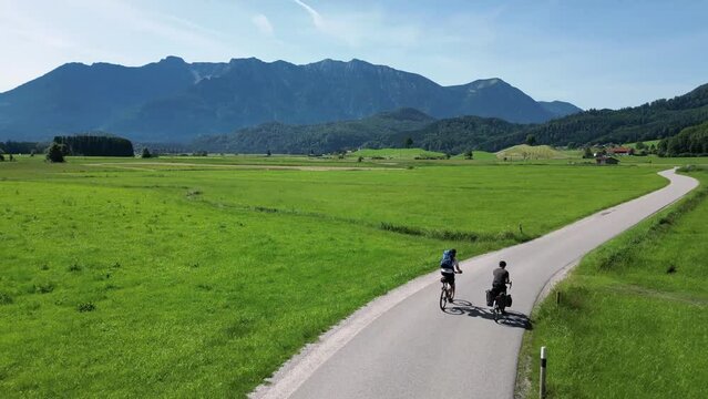 Two cyclists riding through a landscape with mountains in Bavaria