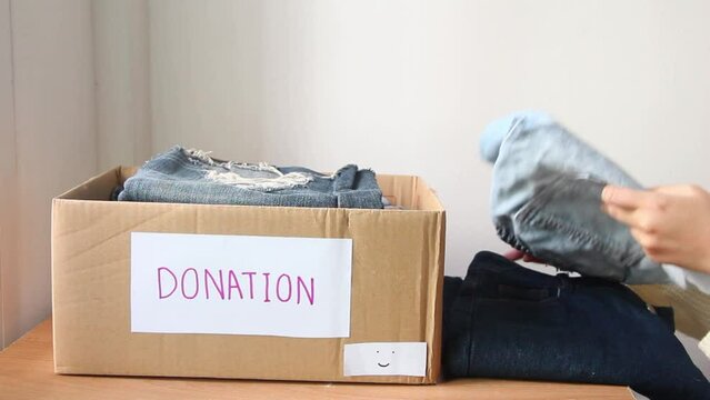 Female put gather clothes in box make donation to needy people.