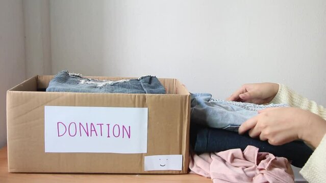 Female put gather clothes in box make donation to needy people.