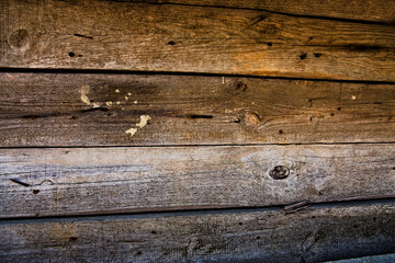 Ściana ze starych , spłowiałych , poszarzałych  desek z licznymi " bliznami " po gwoździach i i innych uszkodzeniach .