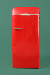 Stylish retro fridge on green background