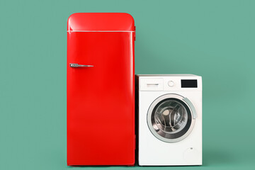Stylish retro fridge and washing machine on green background