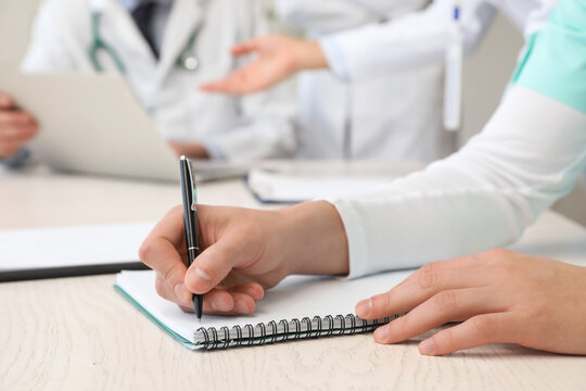 Doctor writing in notebook during meeting in clinic