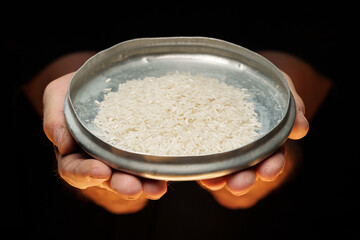 Hands holding a heap of dry rice grain on black background