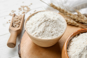 Bowl with wheat flour on wooden board
