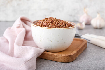 Bowl with buckwheat grains on grey table